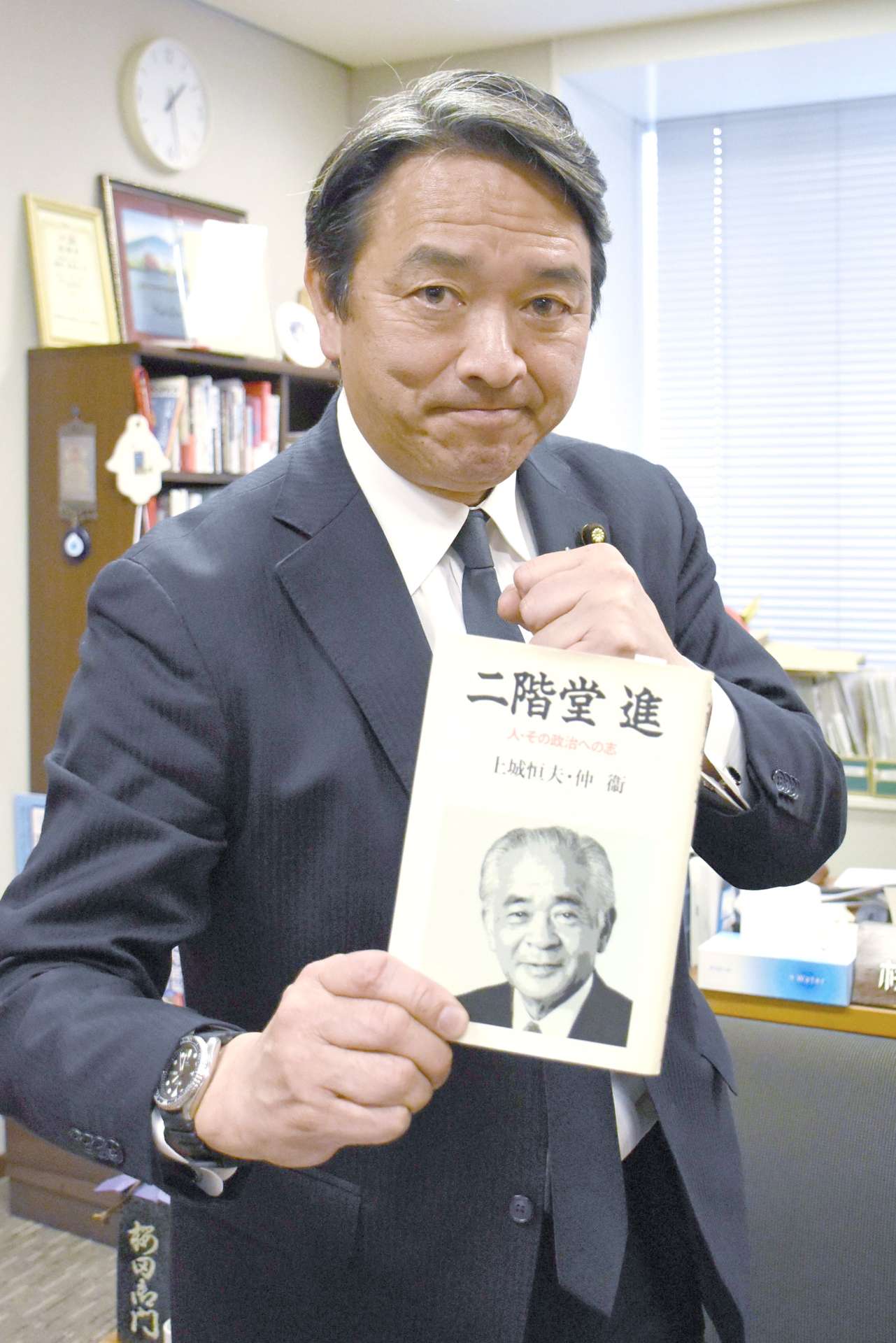 〈関連〉師と仰ぐ二階堂進氏に関する本を手にファイティングポーズをとる榛葉賀津也幹事長＝東京・永田町の参院議員会館