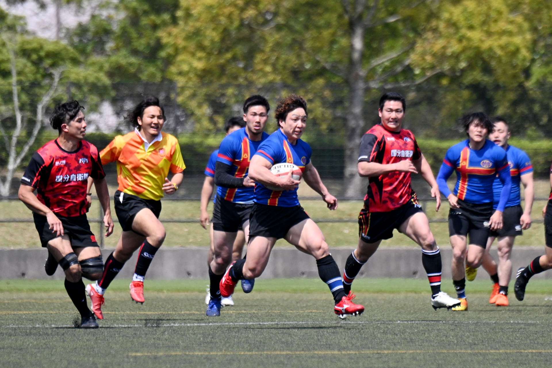 １部の開幕試合で熱戦を繰り広げる選手＝県立サッカー・ラグビー場