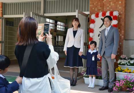 入学式の看板前で記念写真を撮影する新１年生の家族＝７日、鹿児島市の中洲小学校