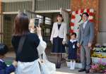 入学式の看板前で記念写真を撮影する新１年生の家族＝７日、鹿児島市の中洲小学校