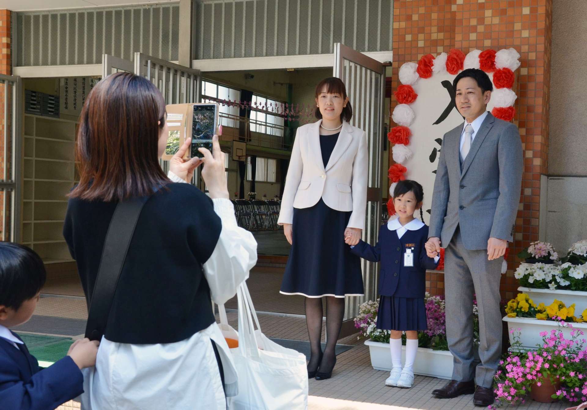 入学式の看板前で記念写真を撮影する新１年生の家族＝７日、鹿児島市の中洲小学校