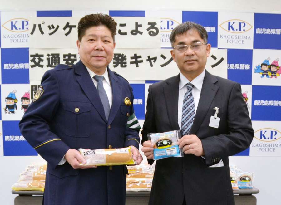 パッケージに標語が記されたパンを手にする黒瀬貴文部長（右）と岩城孝志交通部長＝７日、鹿児島市の県警本部