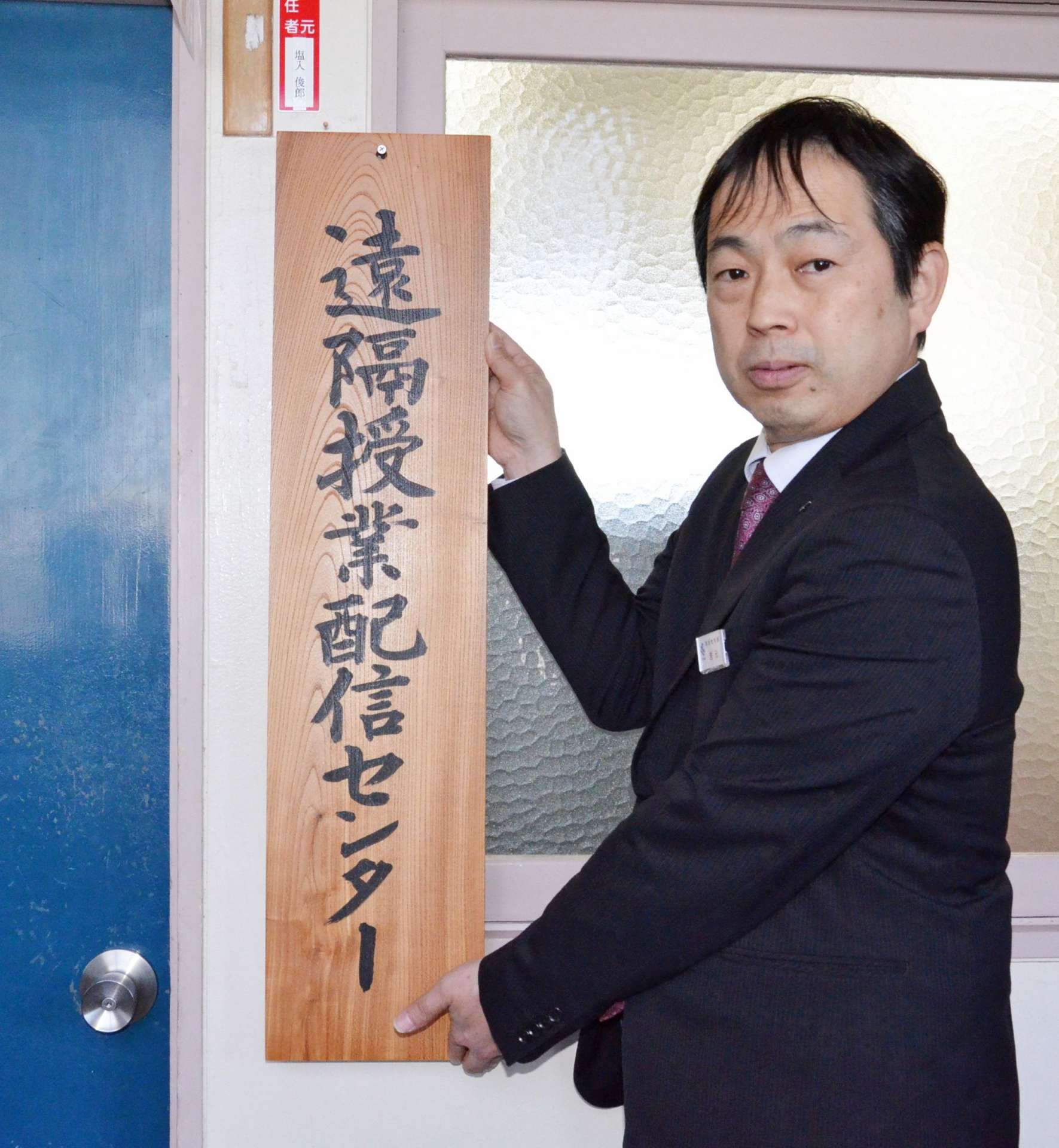 遠隔授業配信センターの看板を設置した県教育委員会の吉元彰一高校教育課長＝８日、鹿児島市の県総合教育センター