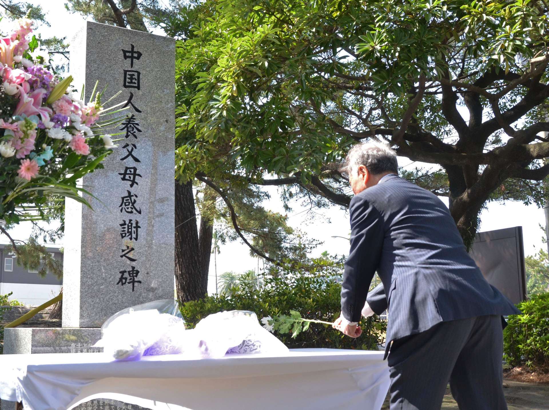 「中国人養父母感謝之碑」に花を手向ける参加者＝６日、鹿児島市の天保山公園
