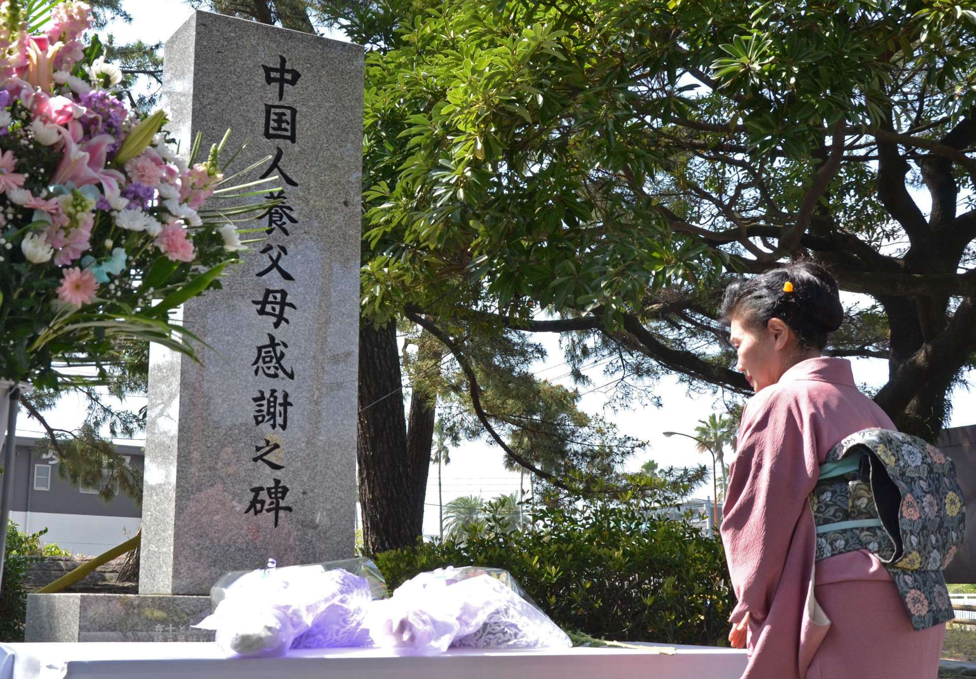 「中国人養父母感謝之碑」に花を手向ける参加者＝６日、鹿児島市の天保山公園