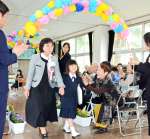 地域住民の拍手の中、退場する竹村心花さん＝８日、天城町の西阿木名小学校三京分校