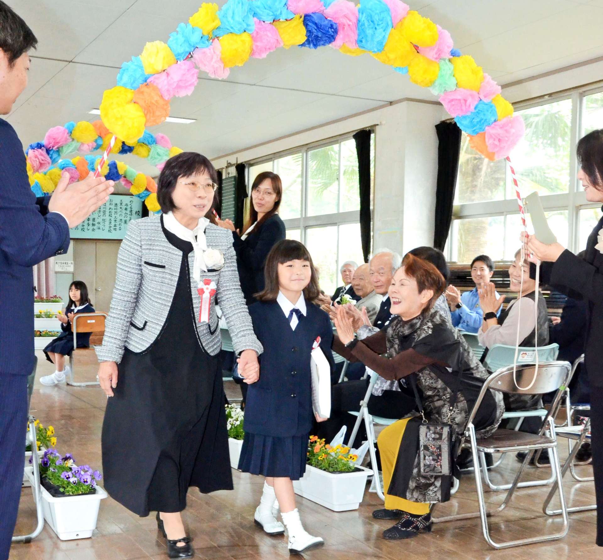 地域住民の拍手の中、退場する竹村心花さん＝８日、天城町の西阿木名小学校三京分校