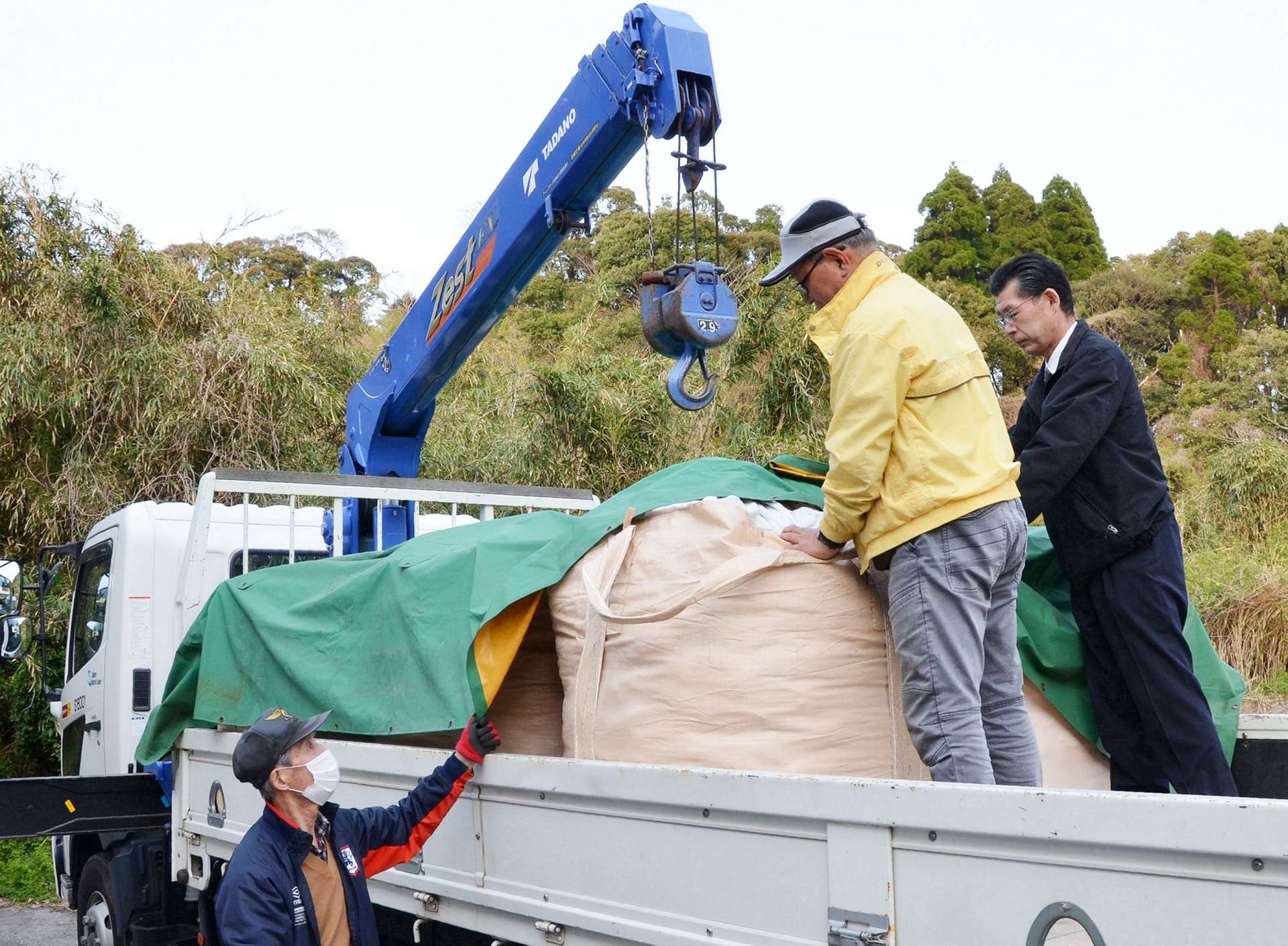 使用済み使い捨てカイロを積み込む松木薗利範さん（中央）ら＝日置市伊集院