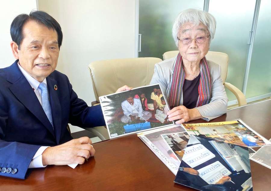 カンボジアの小学校の様子を説明する「いっしょき学校を作いもんそ会」の弓場秋信会長（左）と田野邉稔子副会長＝鹿児島市の弓場貿易