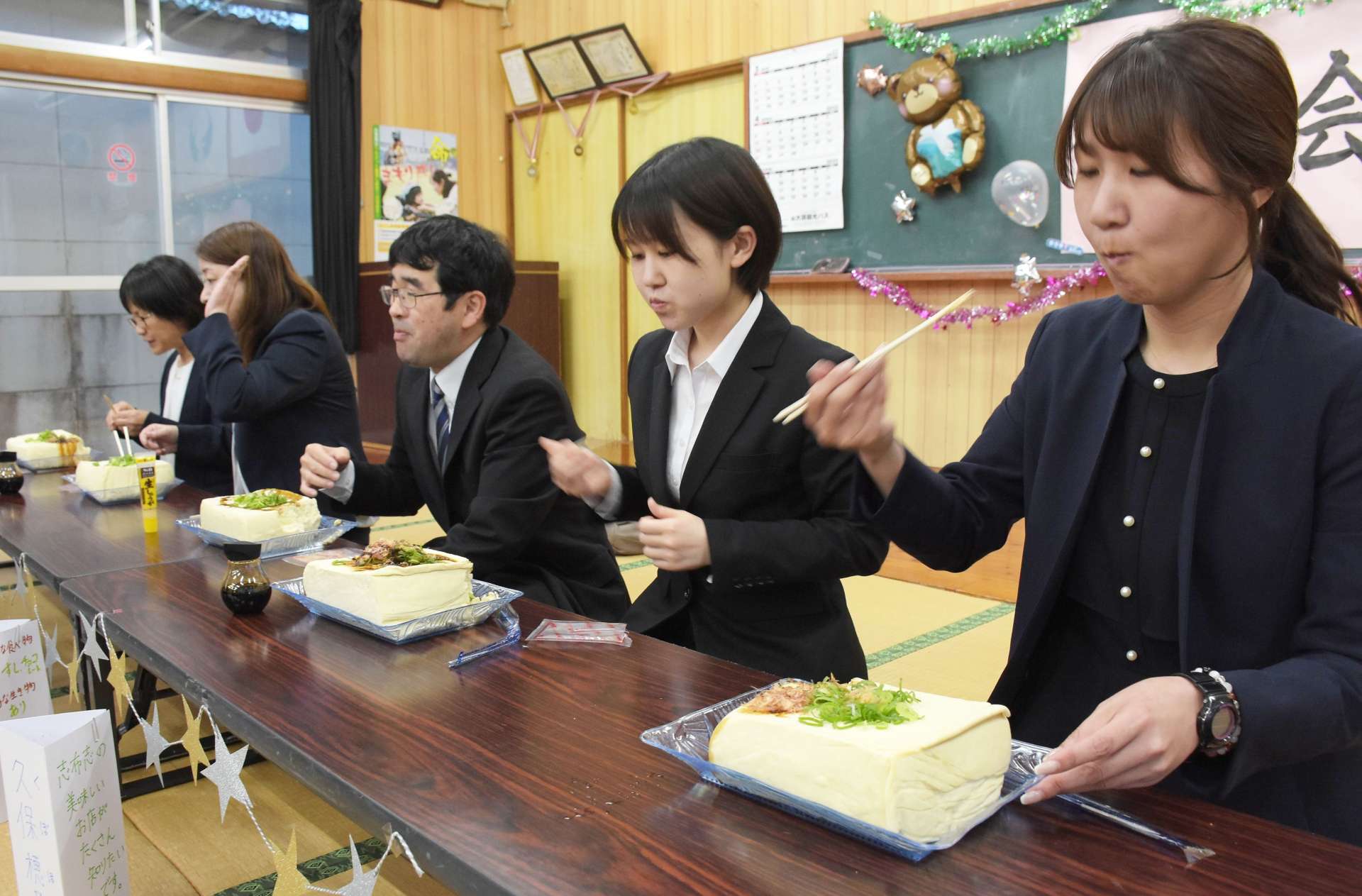 巨大な豆腐を味わう野神小の先生たち＝１１日、志布志市有明の野神青少年館