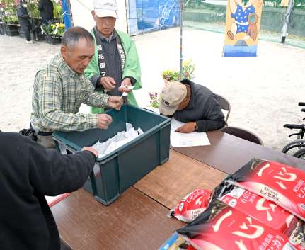 １等コメ１０キロなどの抽選をする鹿児島市木市振興会関係者＝１４日、同市の甲突川左岸緑地帯