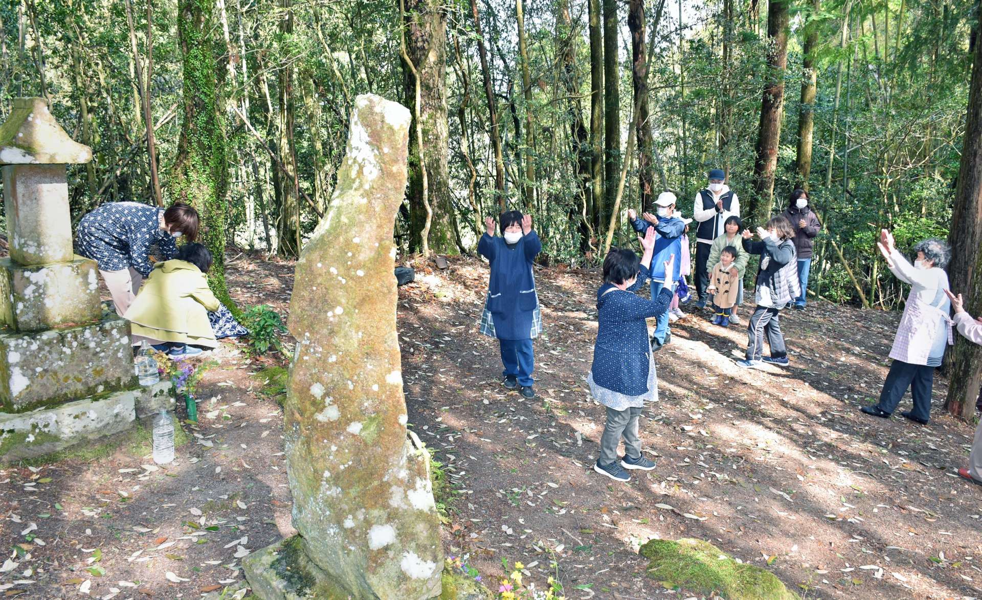 火と水の神さまの石碑に団子を供え、踊りを奉納する住民＝１３日、伊佐市菱刈川南