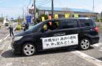 側面に標語を貼った車でスタートする参加者＝１３日、指宿市の指宿警察署