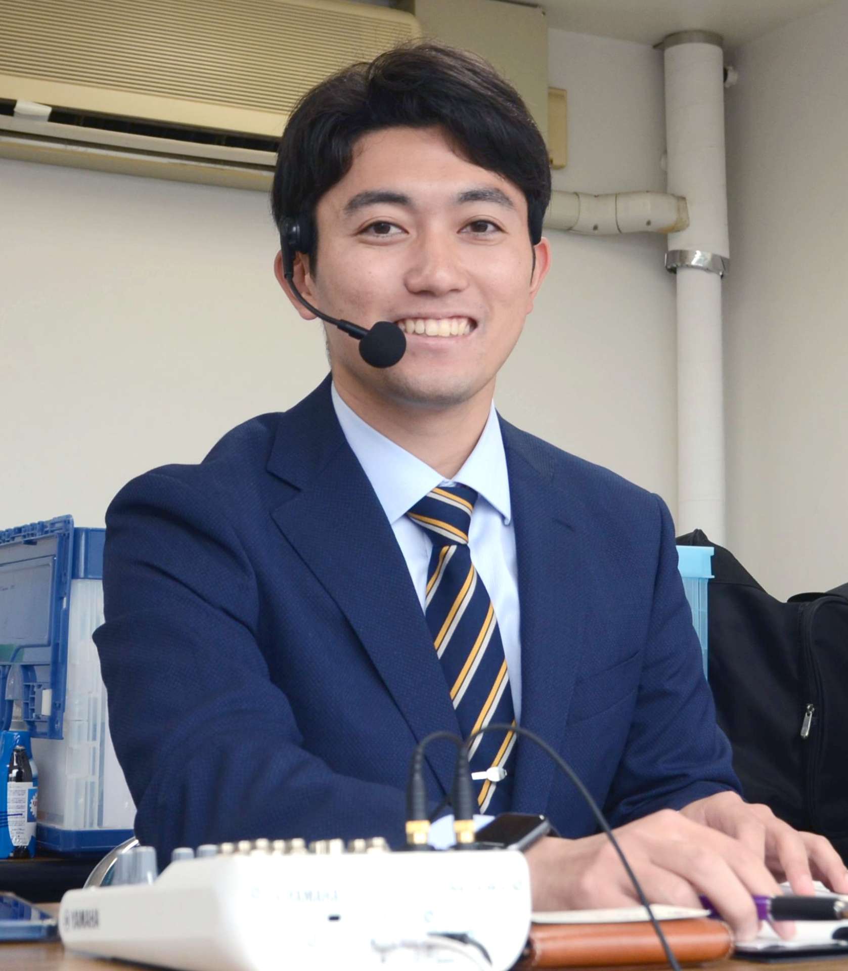 大学野球で実況をする蜂須賀友助さん＝鹿児島市の平和リース球場