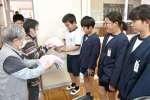 老人ホームの入所者から手縫いのぞうきんを受け取る児童＝１５日、錦江町の大根占小学校