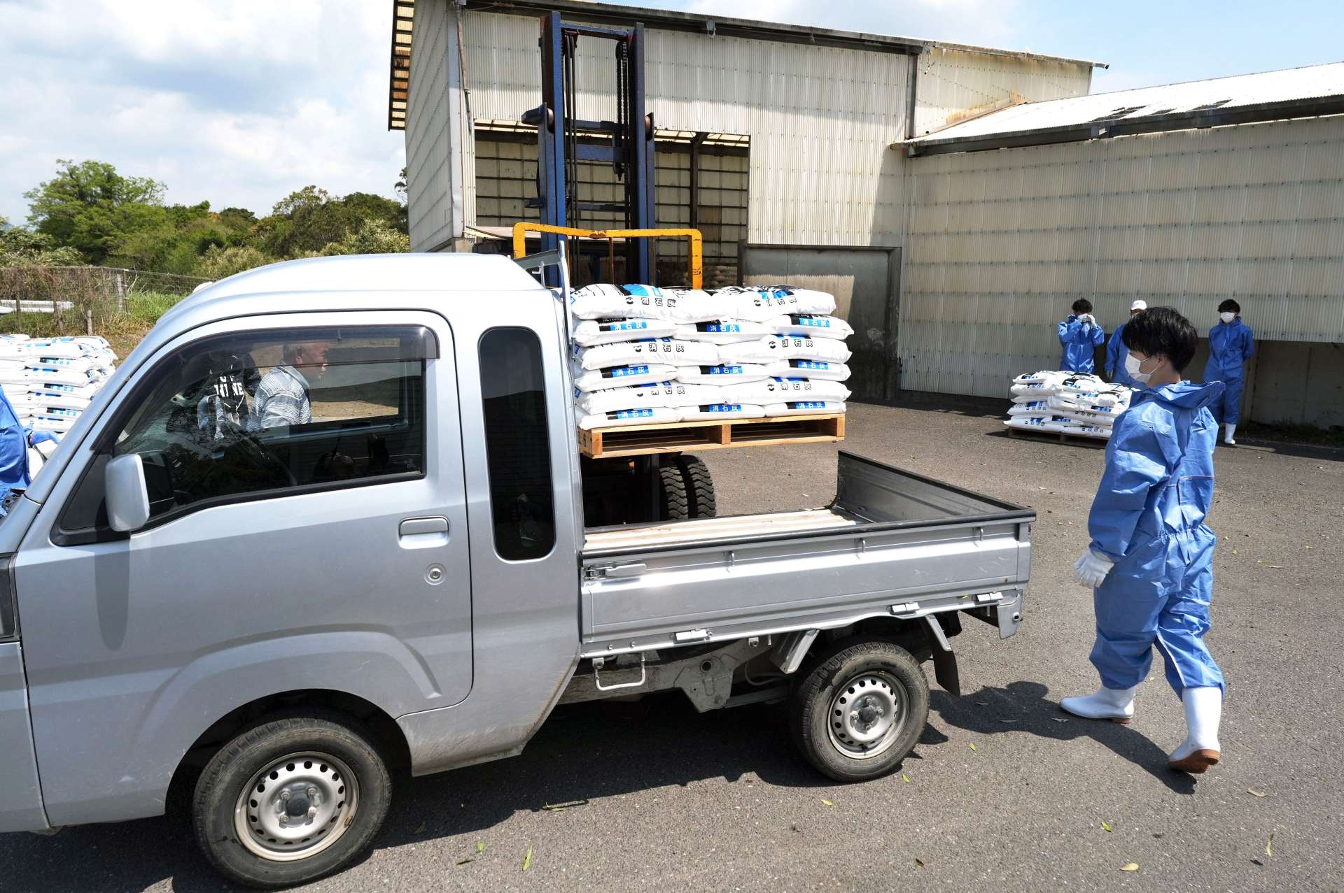 消石灰を軽トラックに積み込む市職員ら＝１７日、鹿屋市祓川町の市畜産環境センター（石本のえる撮影）