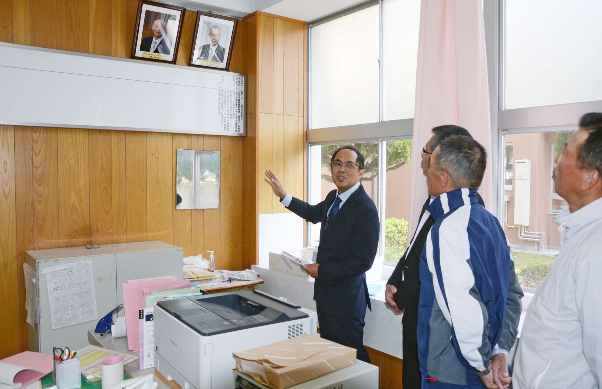 寄贈した校長室の沿革史ボードを見る旧日吉中学校卒業生ら（右３人）＝日置市の日吉学園