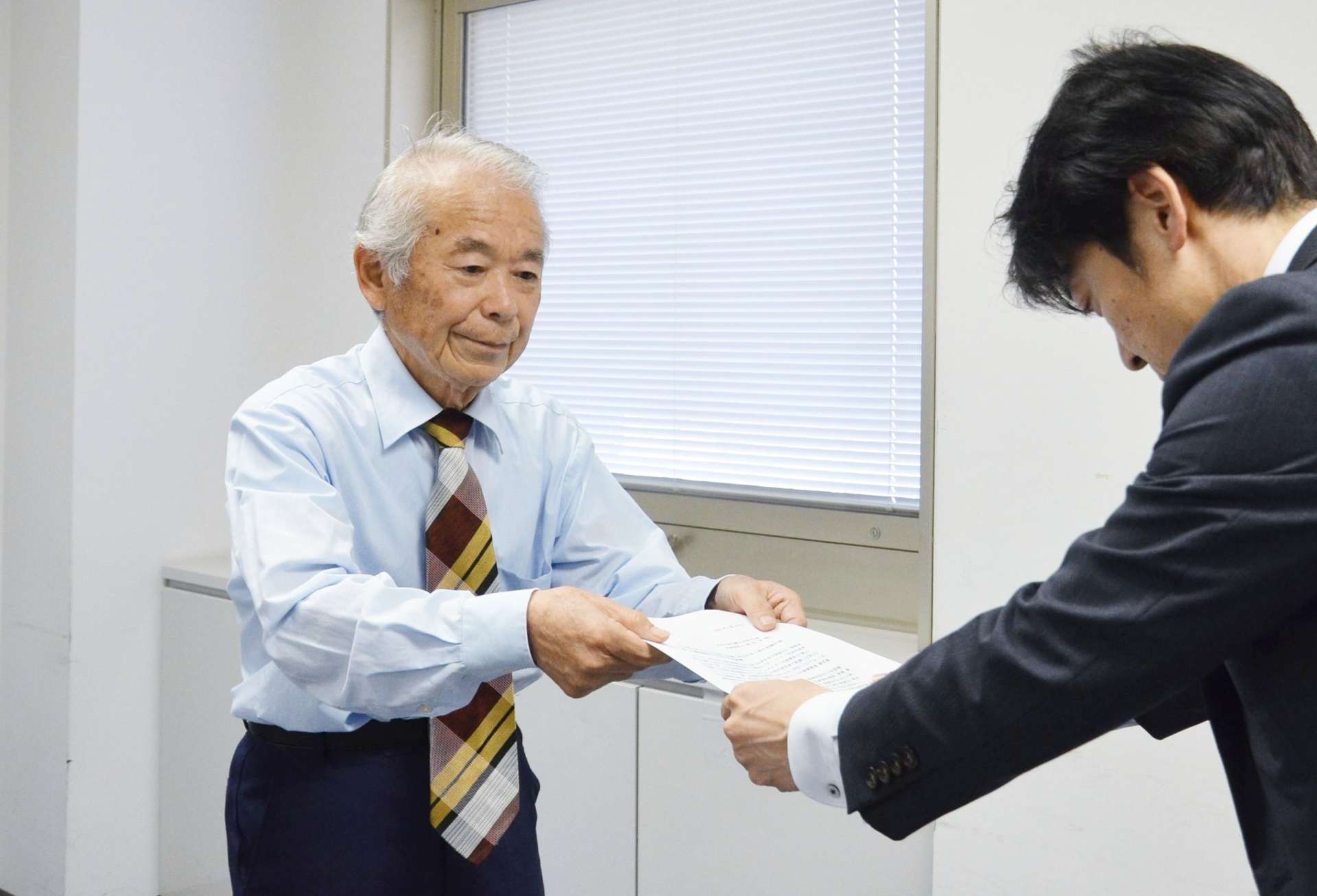 鹿児島県の担当者に要請書を手渡す堀浩一郎代表世話人（左）＝１８日、県庁