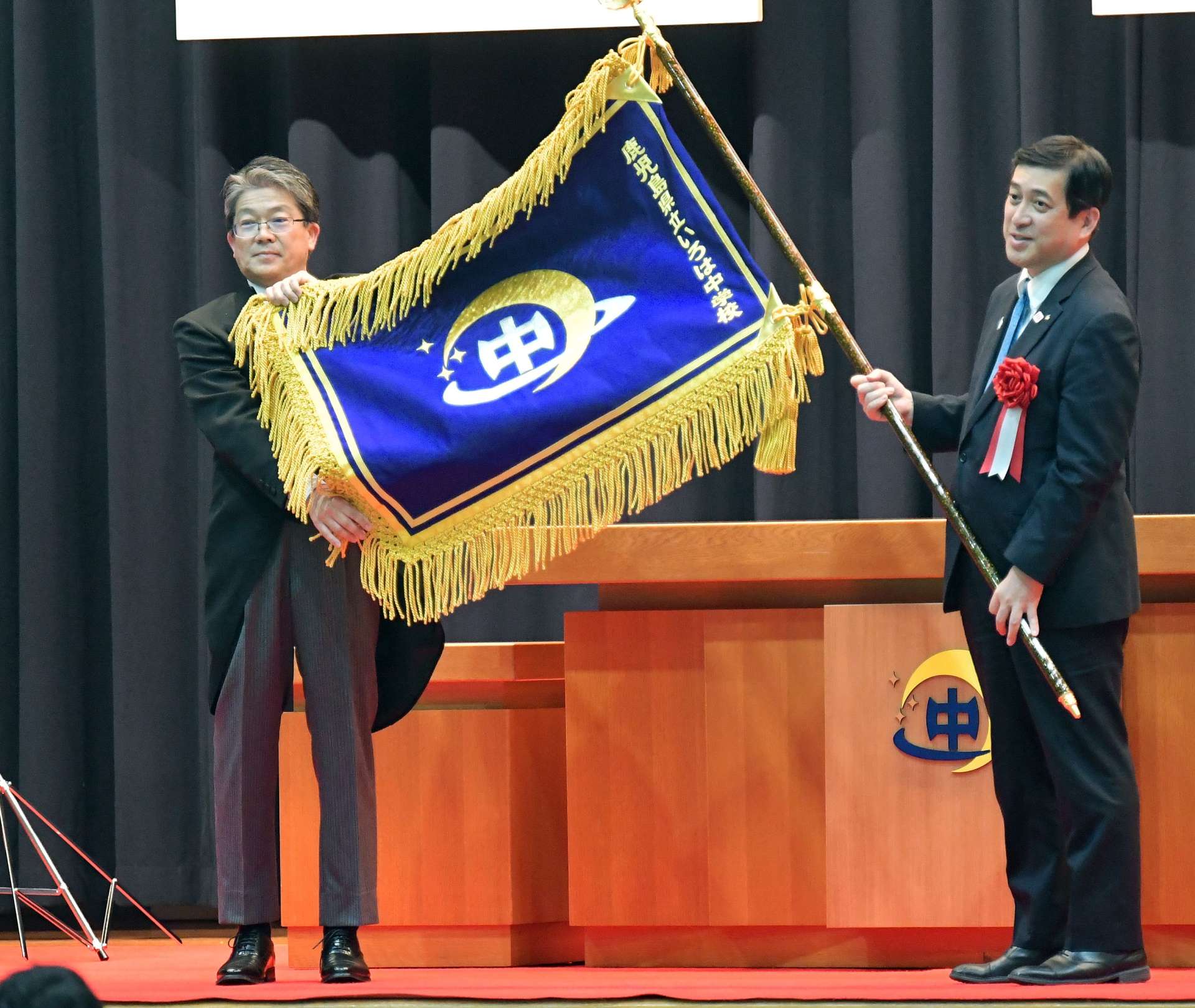塩田康一鹿児島県知事から校旗を受け取り披露するいろは中学校の加藤淳一校長＝１８日、鹿児島市西谷山１丁目の同校