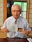 当時の写真などを手に体験を語る宇都口栄市さん＝出水市上鯖渕