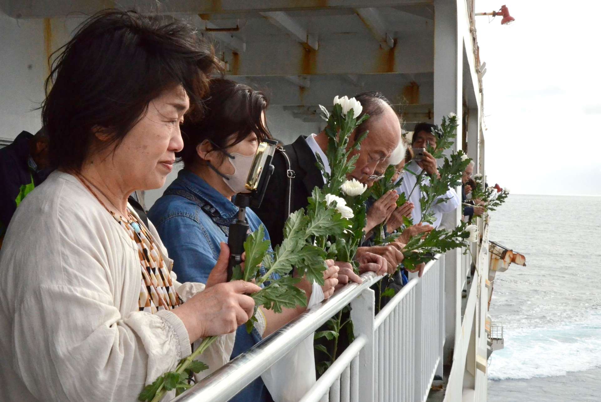 沈没海域で黙とうをささげる遺族＝１９日、徳之島町亀徳沖