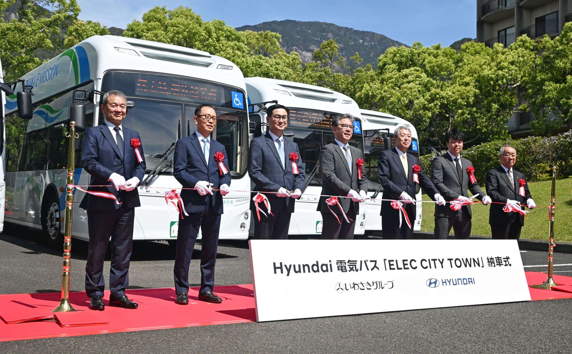 電気バス納車式でテープカットする岩崎グループや現代自動車の関係者ら＝２１日、屋久島町尾之間の屋久島いわさきホテル