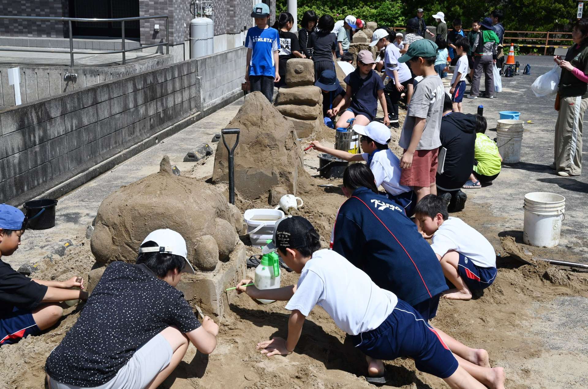 砂の彫刻に挑む子どもたち＝１９日、南さつま市加世田麓町