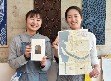 〈別カット〉イワシビルの中でガイド本と地図を手にする松出莉子さん（左）と泉野由起さん＝阿久根市鶴見町