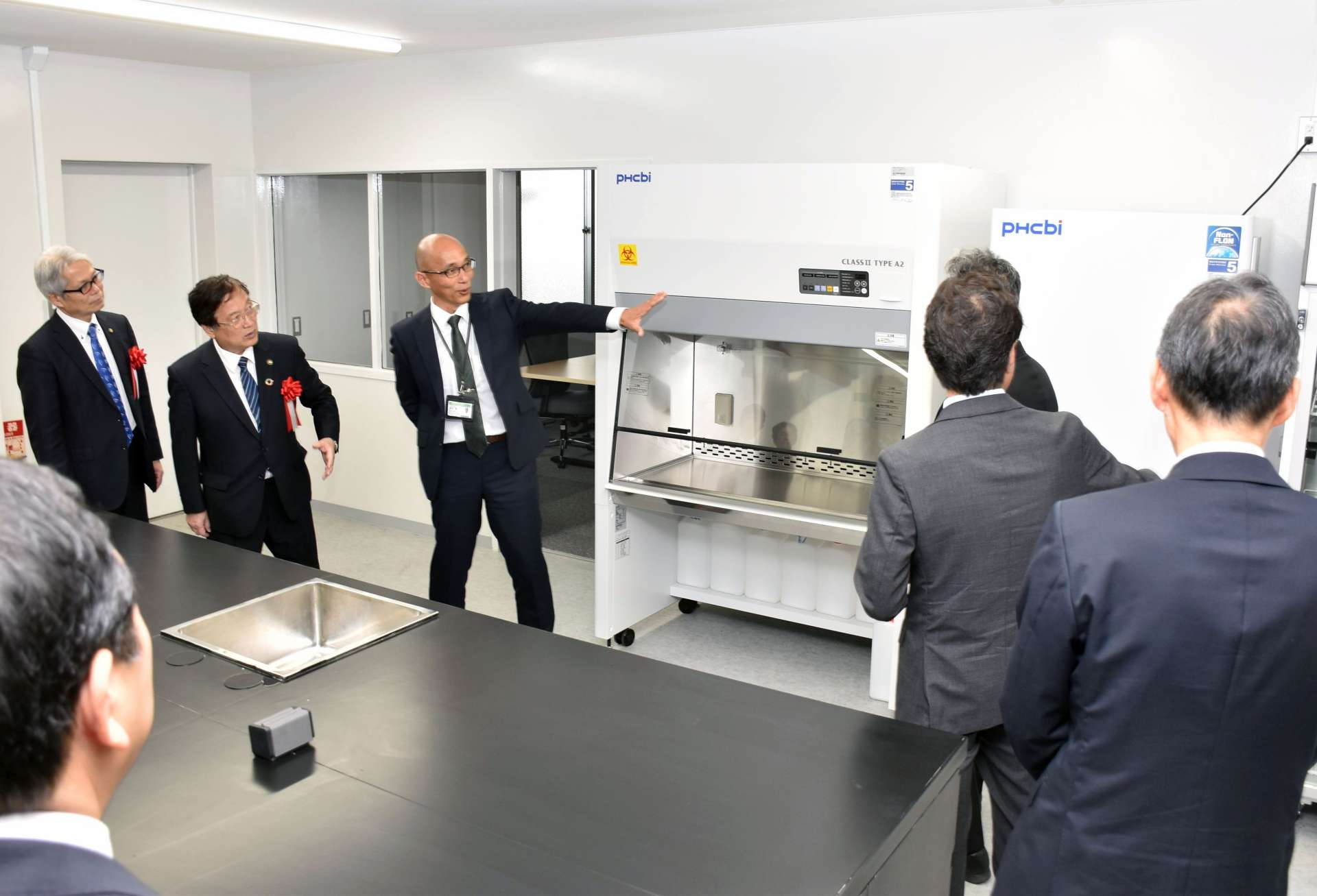 開設した「鹿児島大学サテライトラボ」を見学する関係者＝２２日、薩摩川内市のサーキュラーパーク九州