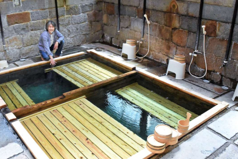 再開する湯川内温泉かじか荘「下の湯」で、湯を確かめる山口貴史代表＝出水市武本