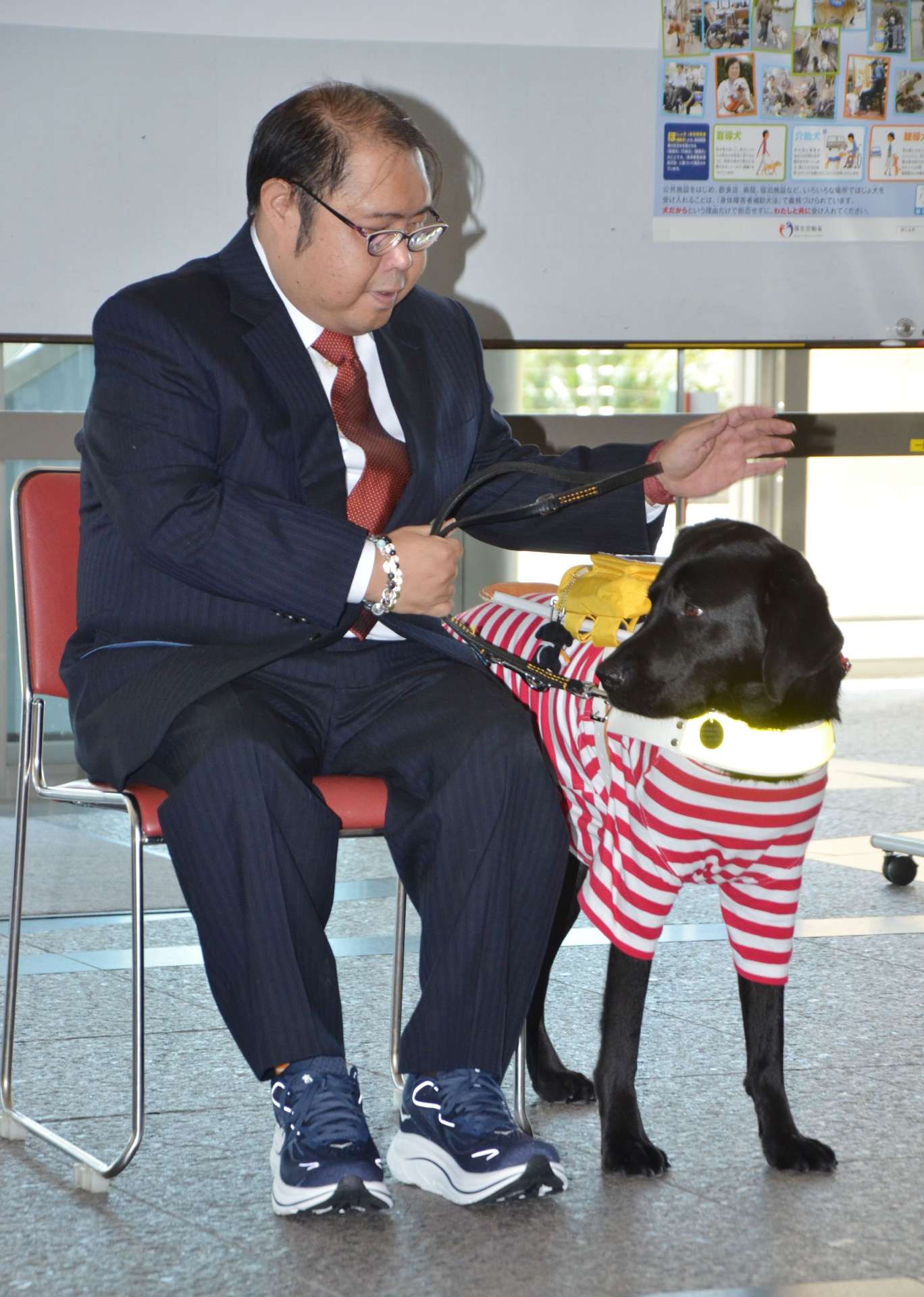 盲導犬のフィルと給付式に臨む川崎清之さん＝２４日、鹿児島県庁