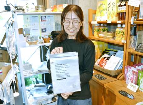 モバイルバッテリ－用の防水ポーチを手にする防災アンテナショップ「カフェ茶花」の吉永めぐみさん＝鹿児島市易居町