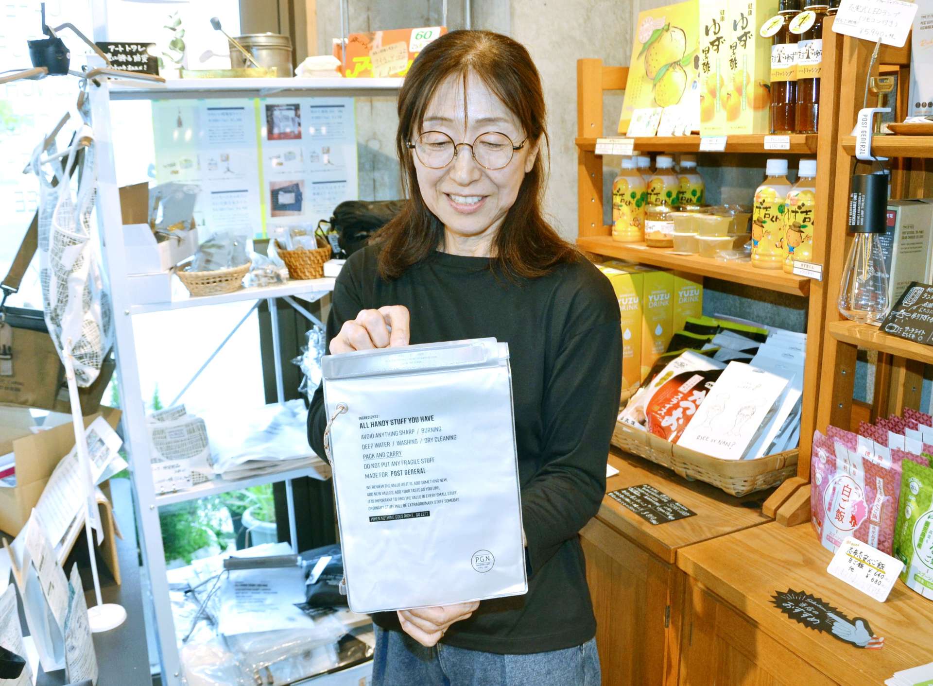 モバイルバッテリ－用の防水ポーチを手にする防災アンテナショップ「カフェ茶花」の吉永めぐみさん＝鹿児島市易居町