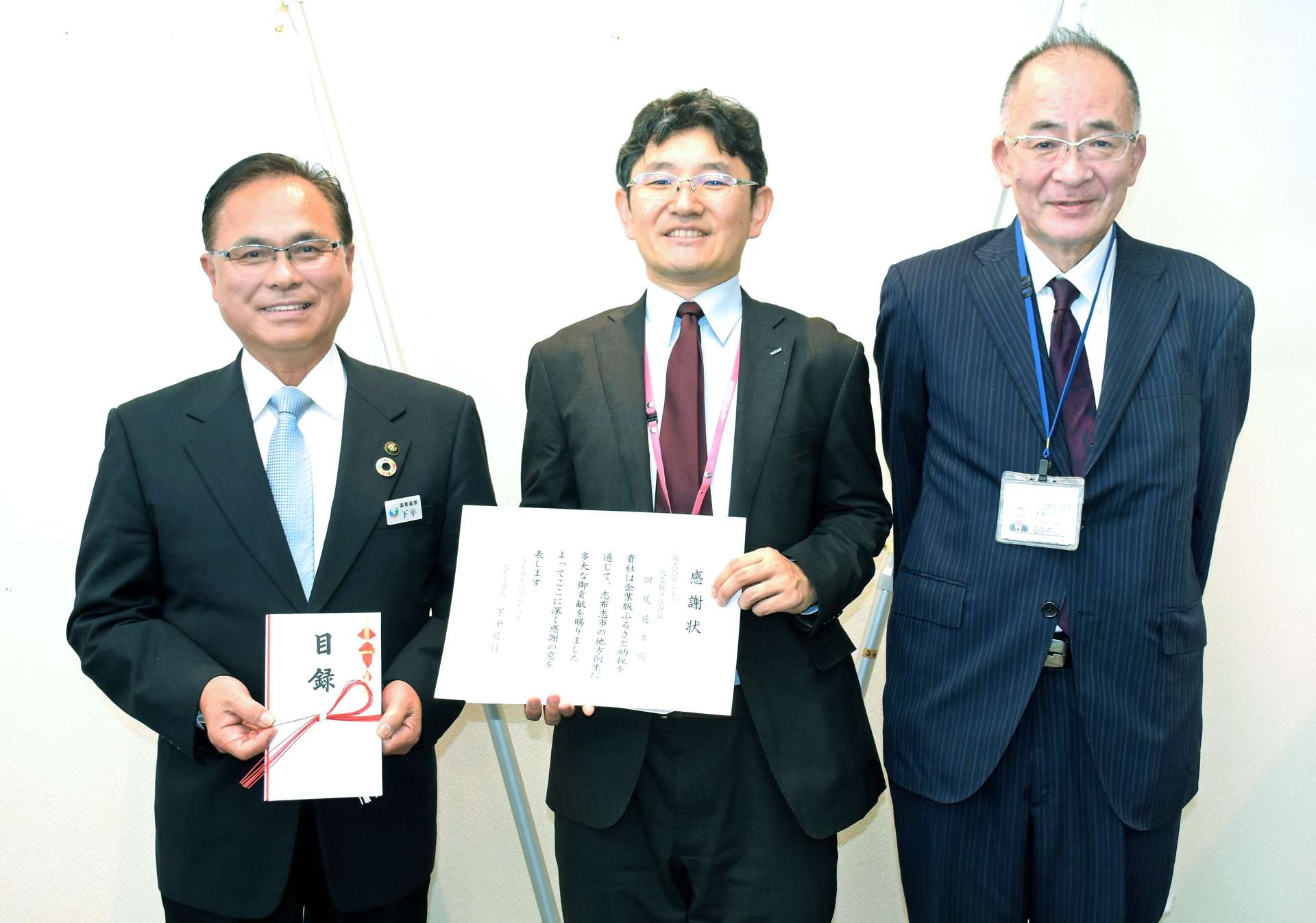 志布志市に企業版ふるさと納税で骨伝導集音器を寄付したムトウの関係者（右２人）＝２４日、志布志市役所