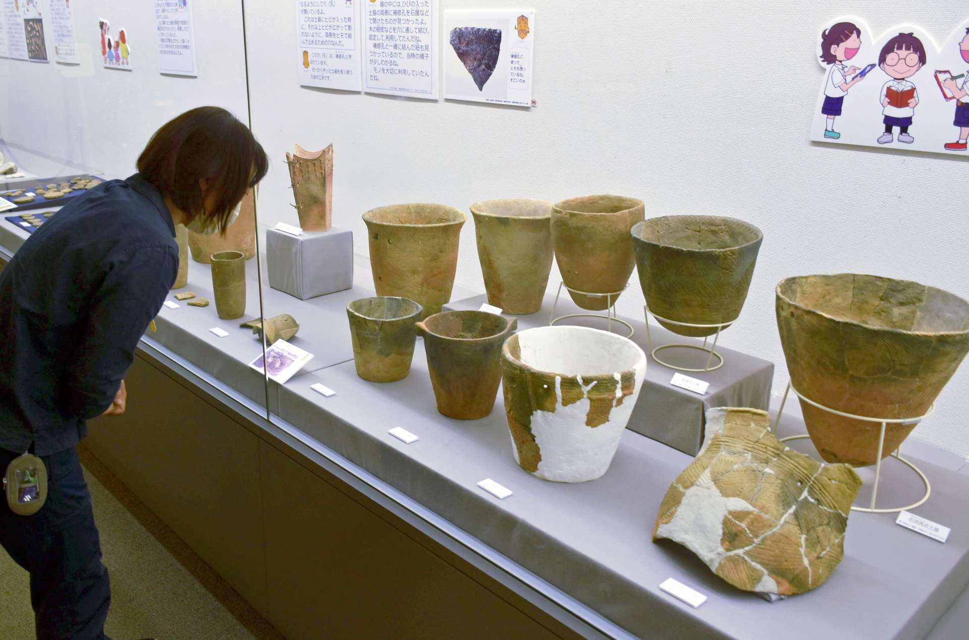 補修用の穴がある土器が並ぶ会場＝２５日、霧島市の上野原縄文の森