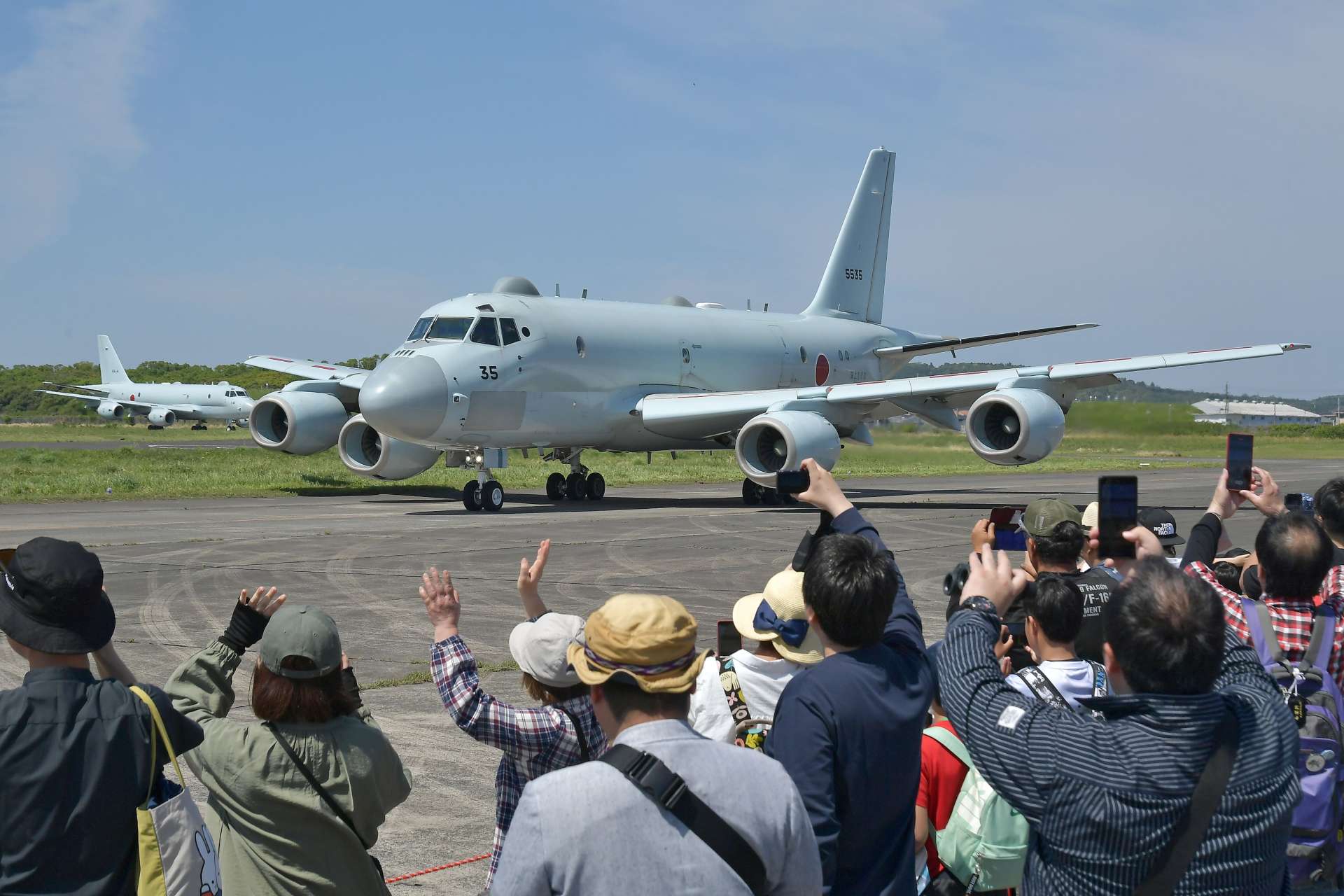海上自衛隊のＰ１哨戒機に手を振ったりする来場者＝２７日午前１０時２７分、鹿屋市の海上自衛隊鹿屋航空基地