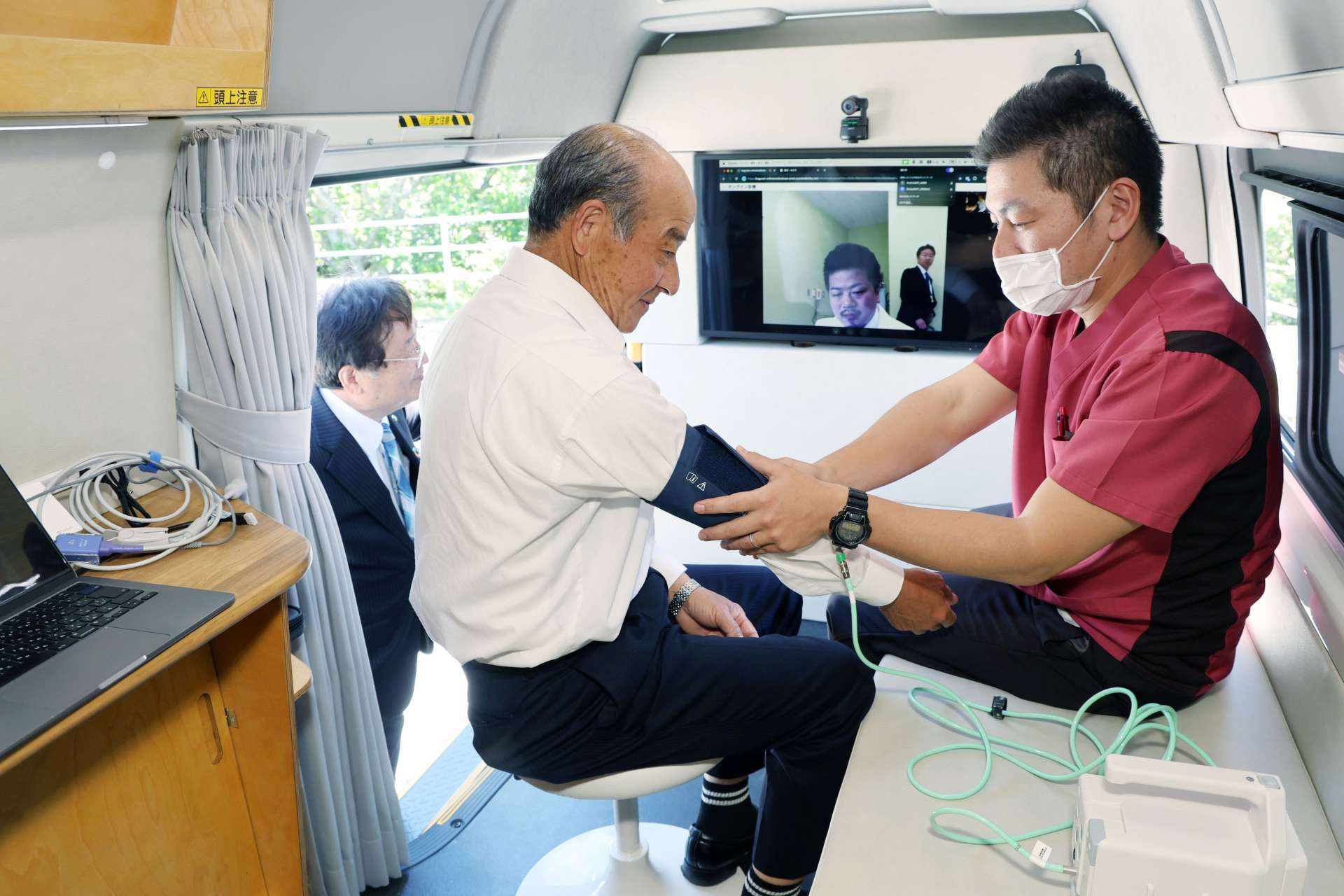 導入した車両を使って離れた医師によるオンライン診療を体験する出席者＝２７日、薩摩川内市の下甑手打診療所
