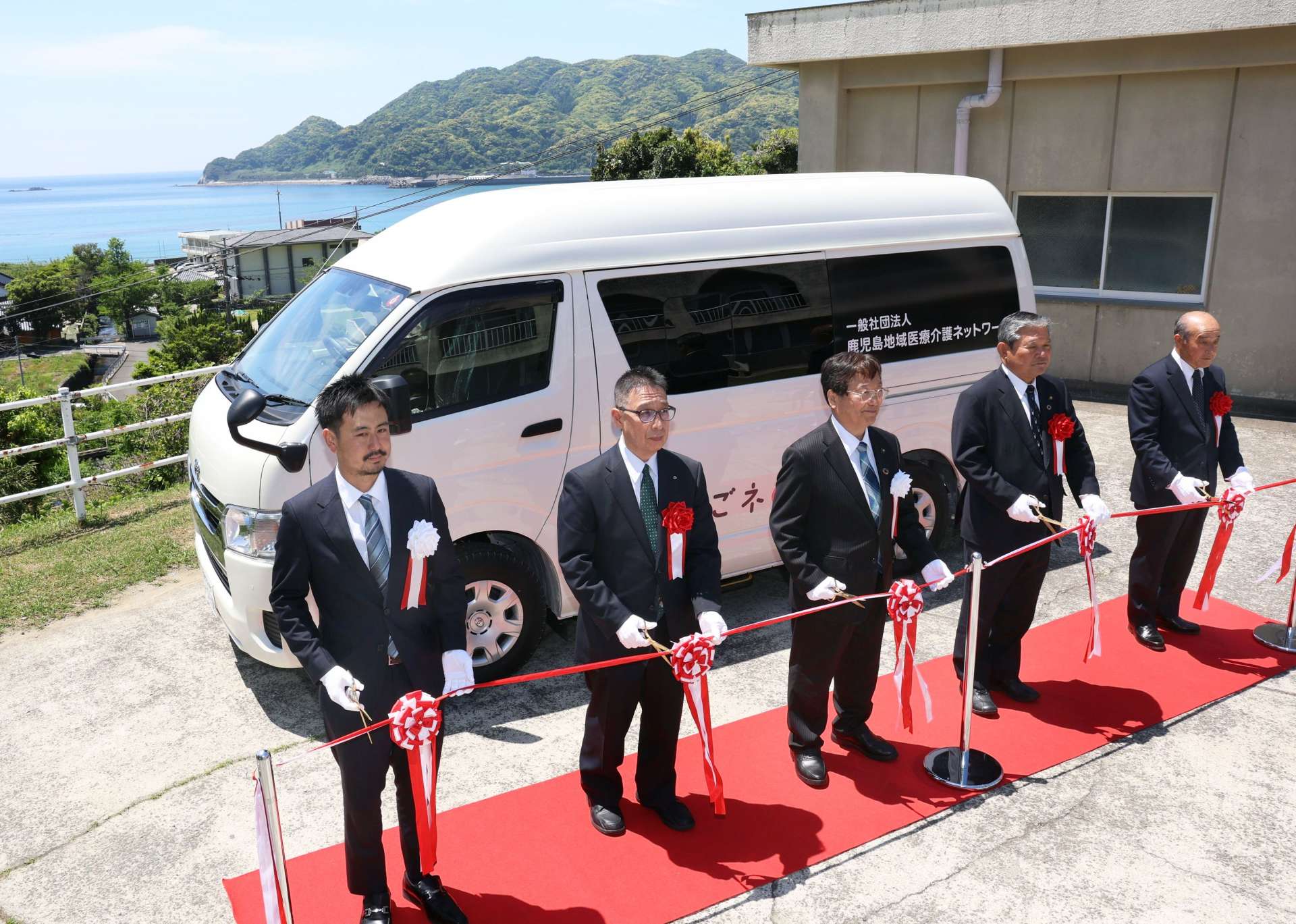医療ＭａａＳの車両の運用開始を祝いテープカットする関係者＝２７日、薩摩川内市の下甑手打診療所
