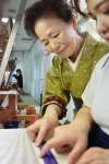 生徒に大島紬の織り方を指導する榮夏代さん＝奄美市