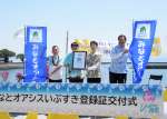 みなとオアシスいぶすきの登録証とのぼり旗を手に祝う関係者＝２９日、指宿市の指宿港海岸