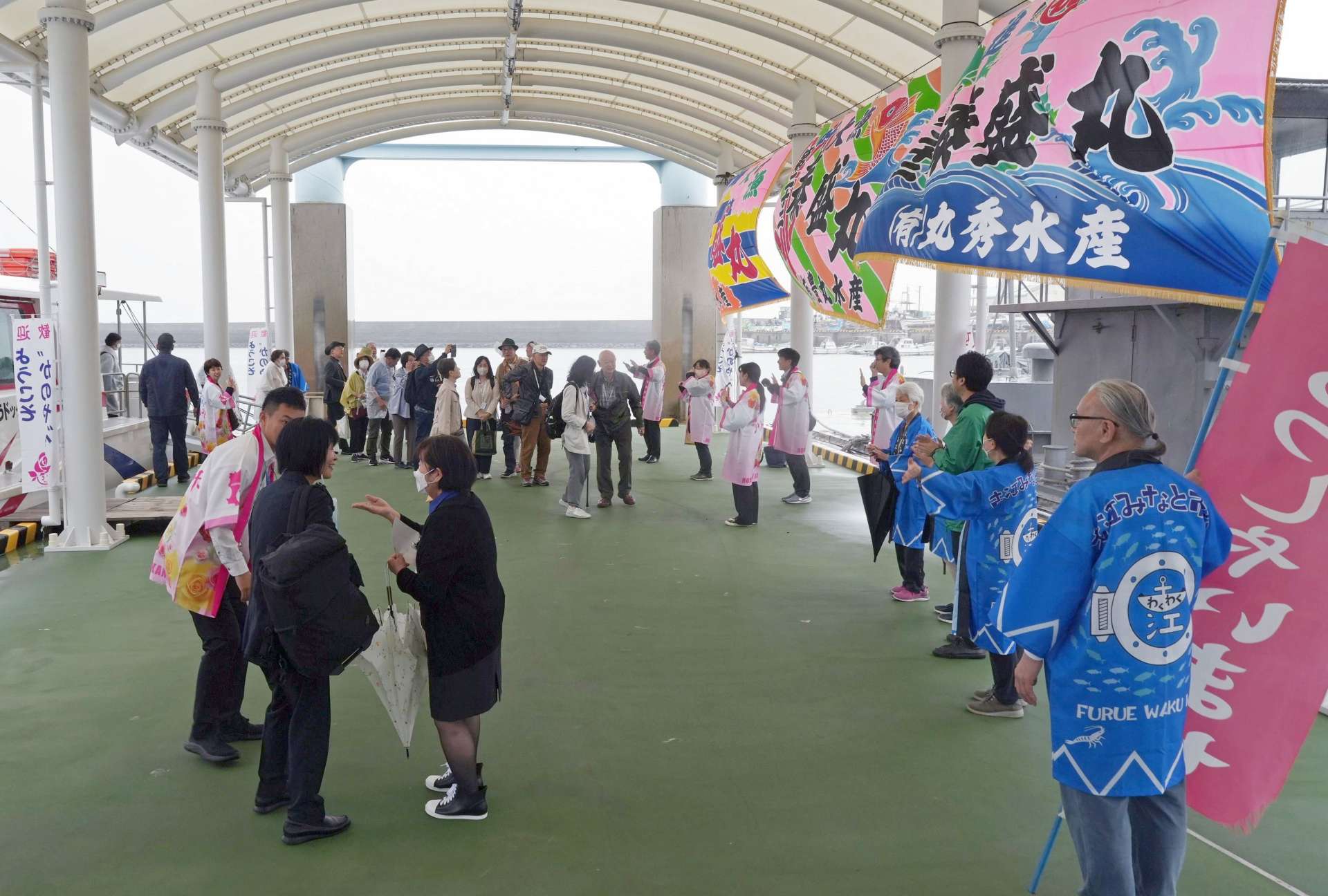 高速船から降りたツアー客を出迎える地元住民ら＝鹿屋市古江町