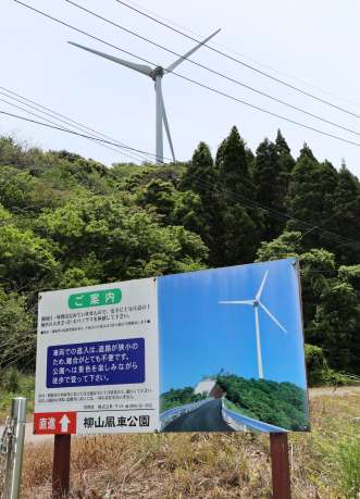 〈関連〉風車（後方）のある公園を案内する看板。この先で立ち入り禁止となった＝３日、薩摩川内市高江町