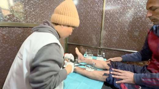攻撃で足を負傷した患者の包帯を交換する中池ともみさん＝２月、ガザ南部ハンユニスのナセル病院