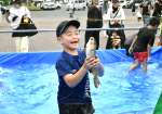 コイのつかみ取りに挑戦する子ども＝５日、垂水市田神の垂水中央運動公園