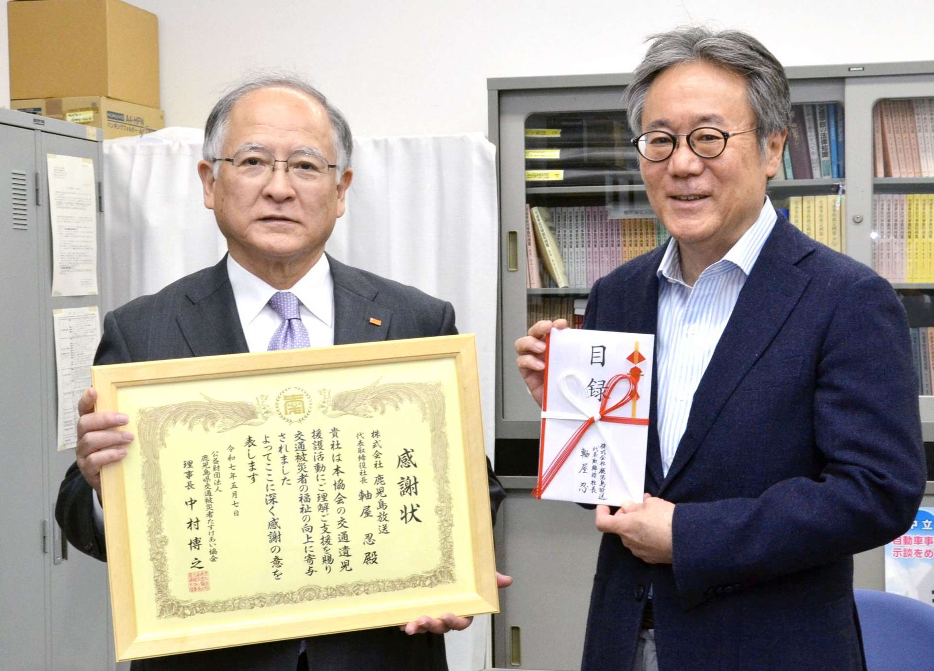 プロ野球公式戦の招待券を寄付したＫＫＢ鹿児島放送の軸屋忍社長（左）＝７日、鹿児島県庁