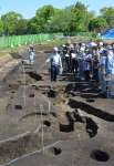 ３２年前に発掘された隣接遺跡と断面がぴったり一致した周溝状遺跡の説明に耳を傾ける参加者＝都城市早水町