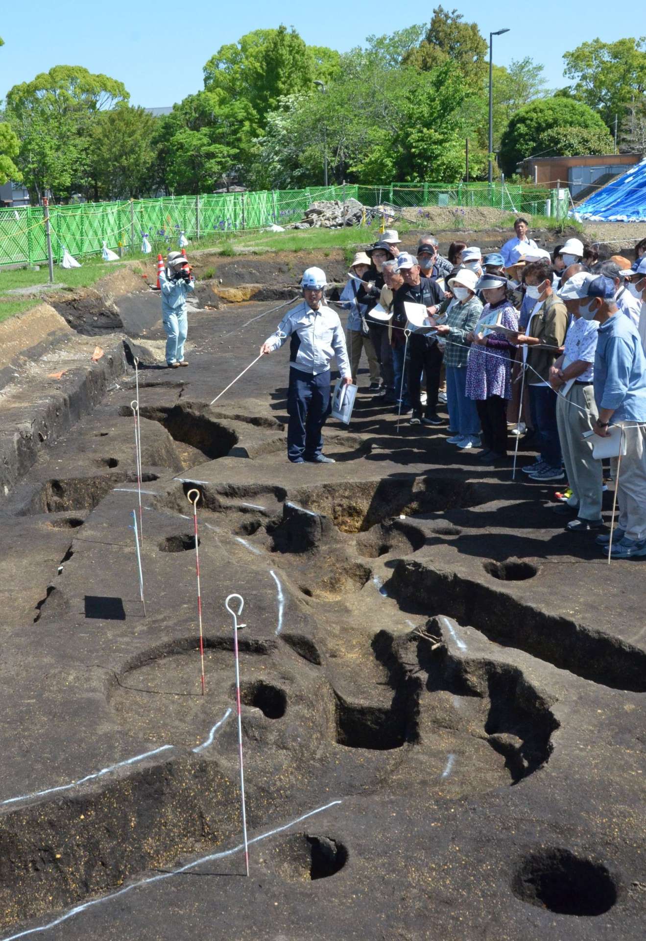 ３２年前に発掘された隣接遺跡と断面がぴったり一致した周溝状遺跡の説明に耳を傾ける参加者＝都城市早水町