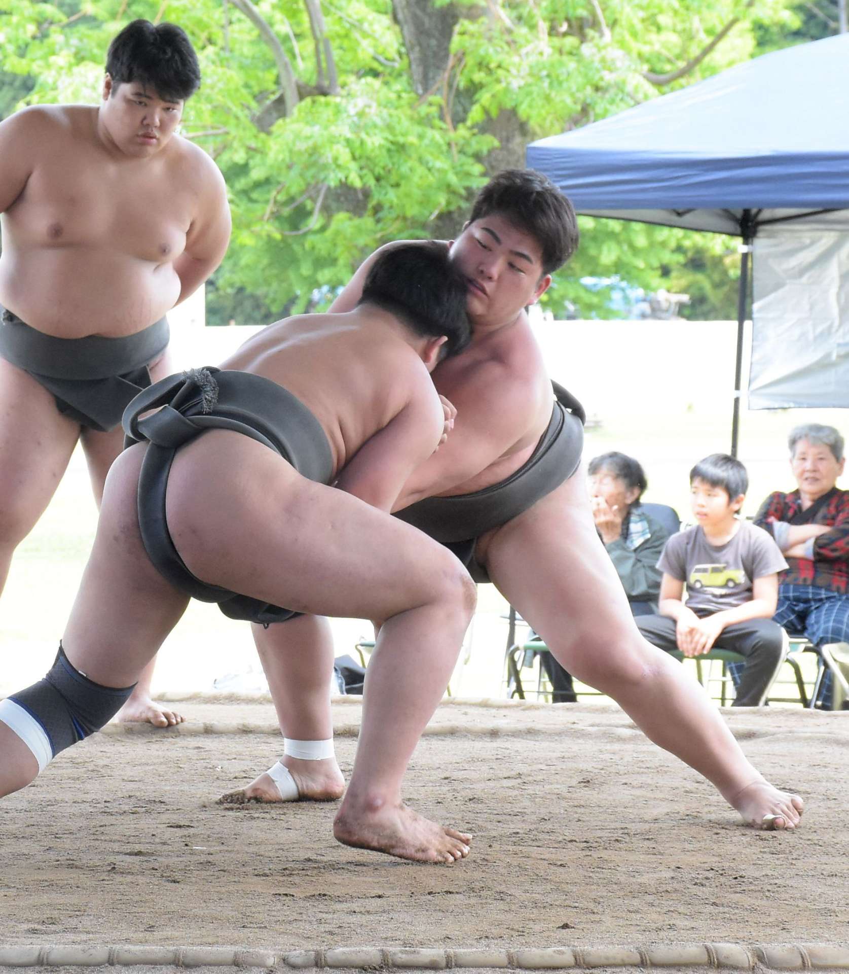 気迫あふれる取組を繰り広げる合同合宿参加者＝３日、志布志市の伊崎田小校庭相撲場