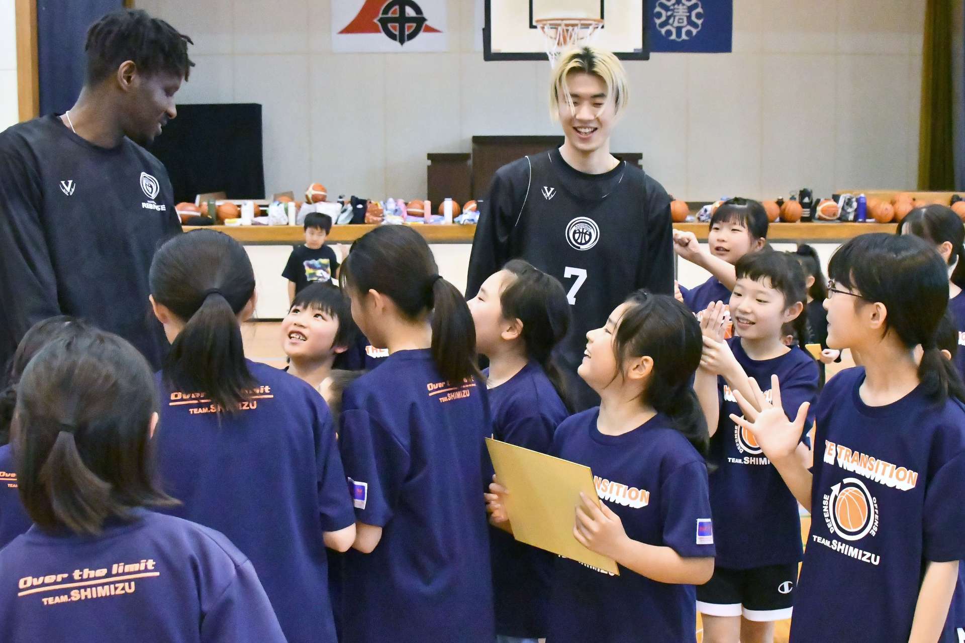子どもたちと交流するレブナイズの伴馬（左）と飴谷＝４月、鹿児島市の清水小学校