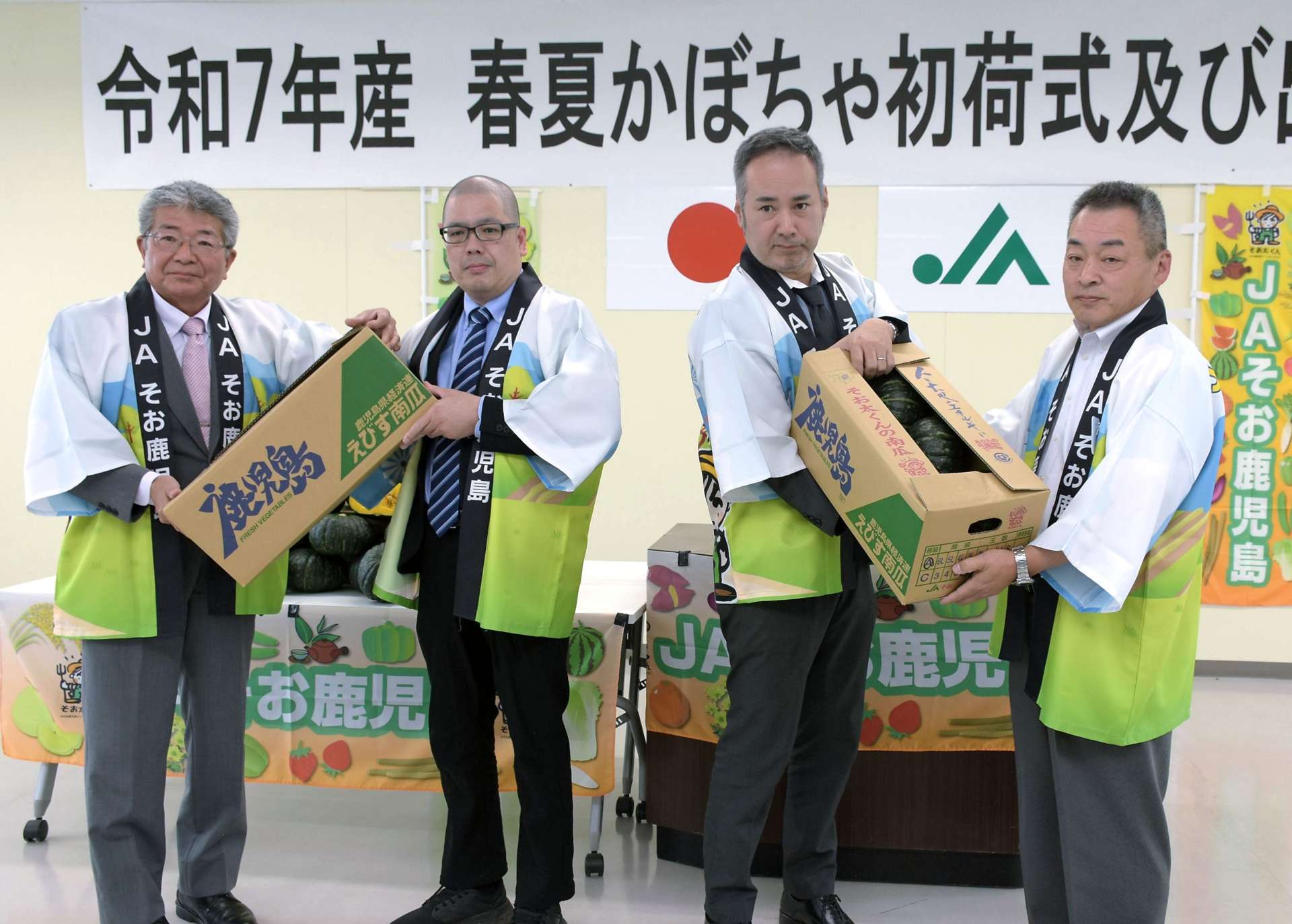 初荷式で市場関係者に「春夏かぼちゃ」を手渡す廣山栄作部会長（左）ら＝９日、志布志市のＪＡそお鹿児島志布志支店